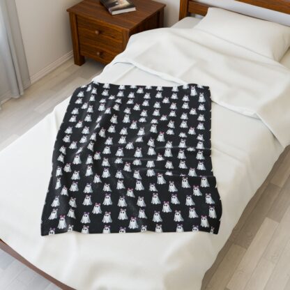Cute ghosts in a white sheet wearing pink and purple bows on velveteen blanket.