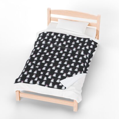Cute ghosts in a white sheet wearing pink and purple bows on velveteen blanket.