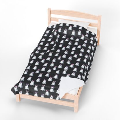 Cute ghosts in a white sheet wearing pink and purple bows on velveteen blanket.