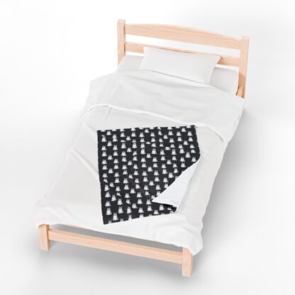 Cute ghosts in a white sheet wearing pink and purple bows on velveteen blanket.
