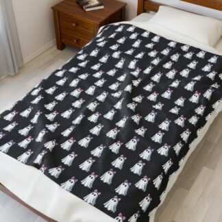 Cute ghosts in a white sheet wearing pink and purple bows on velveteen blanket.